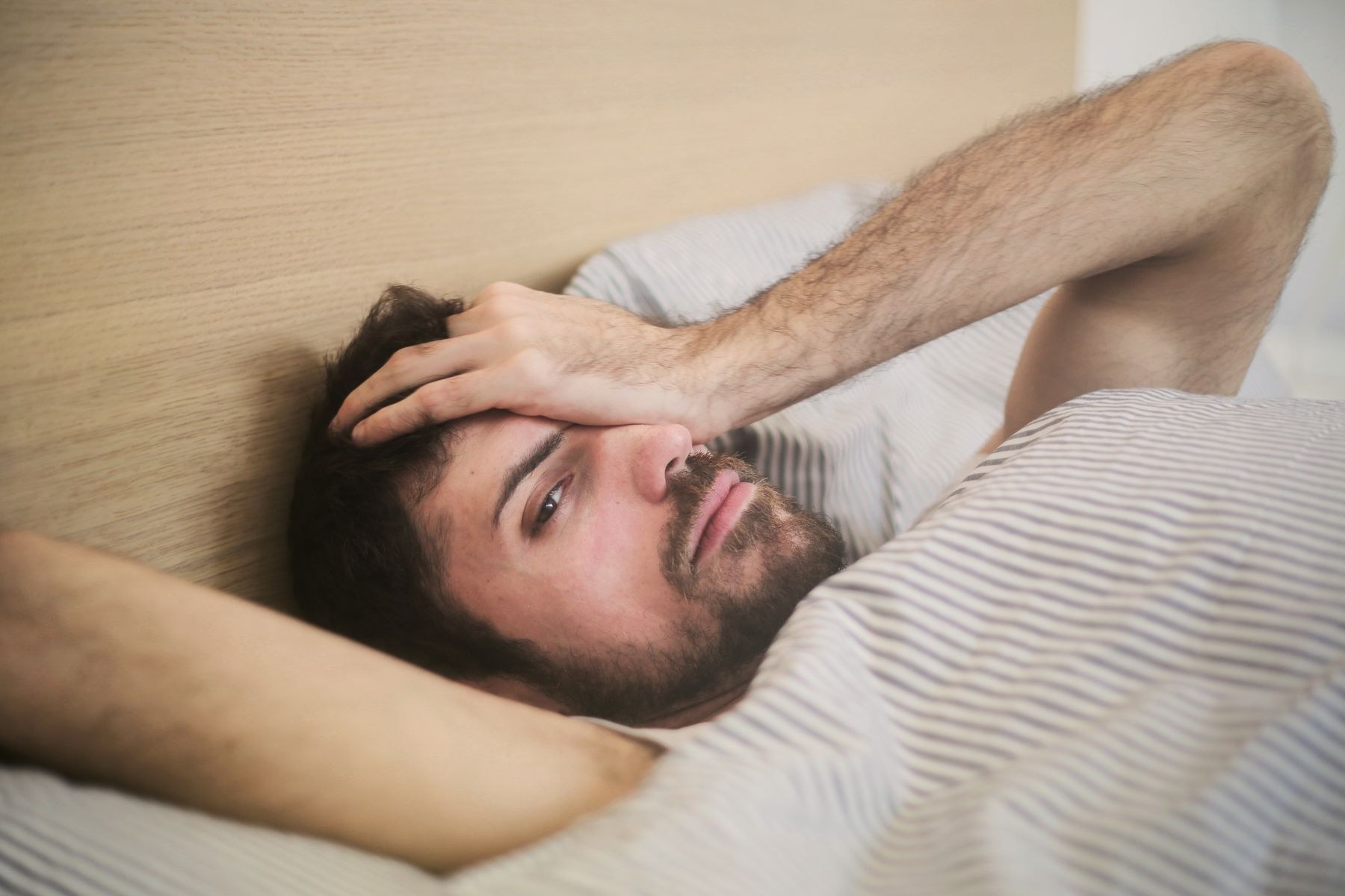 Persona sdraiata a letto al risveglio, immagine illustrativa del bruxismo notturno